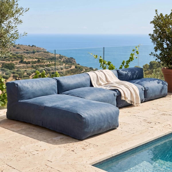 Modulares blaues Outdoor-Sitzsack-Sofa auf einer Steinterrasse am Pool mit Meerblick.