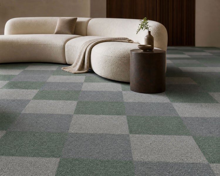 Teppichfliesen in einem Schachbrettmuster aus grünen und grauen Quadraten in einem modernen Wohnzimmer mit hellem Sofa.