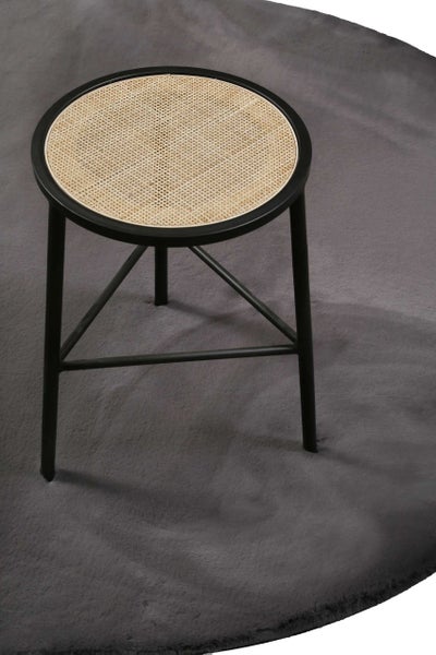 Runder Hocker mit Sitzfläche aus Wiener Geflecht und schwarzem Metallgestell auf einem grauen Teppich.