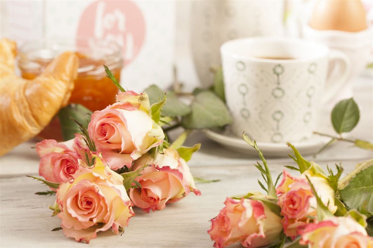 Stillleben mit Rosen, Croissant, Marmelade und einer Tasse Kaffee