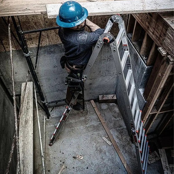 Handwerker auf einer Aluminium-Multifunktionsleiter in einer engen Baustellensituation.