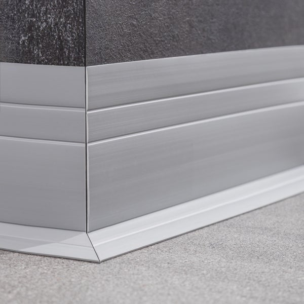 Sockelleiste aus Metall an einer Wand mit dunklen Fliesen als Abschluss zum Bodenbelag