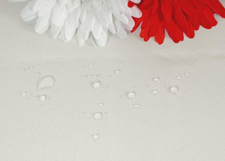 Wassertropfen perlen auf einer wasserabweisenden Stoffoberfläche ab.