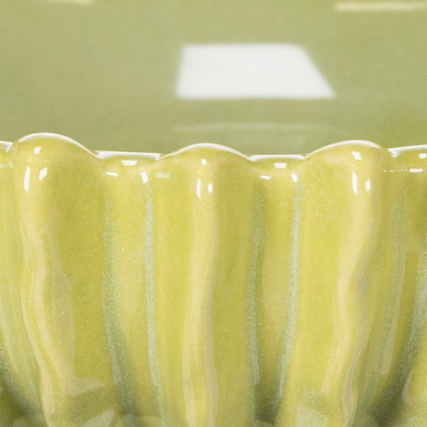 Nahaufnahme einer grünen, gewellten Kuchenform aus Keramik.