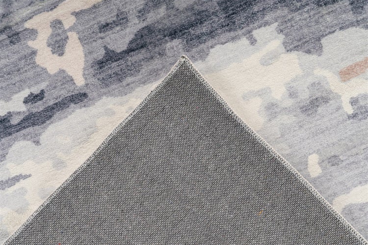 Nahaufnahme eines abstrakt gemusterten Teppichs in Grau und Weiß mit Sicht auf die Oberflächenstruktur und die rutschfeste Rückseite.