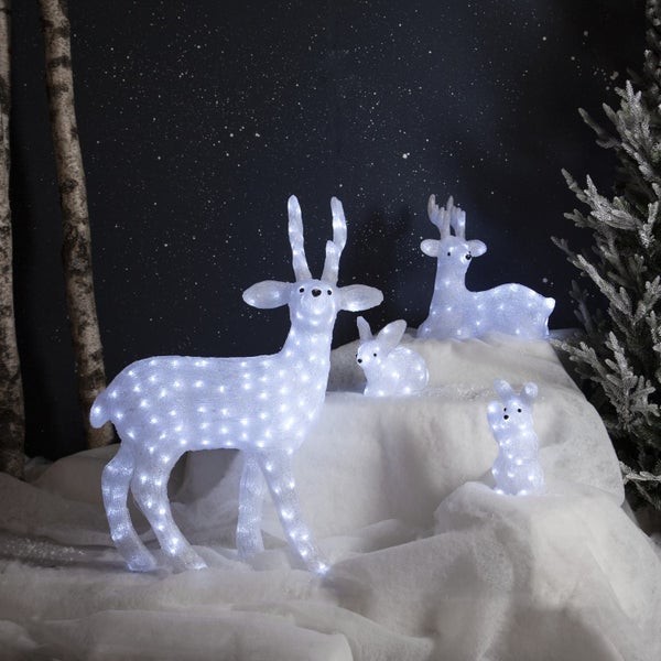 Dekorative Szene mit beleuchteten Hirsch- und Hasenfiguren auf einer Schneedecke