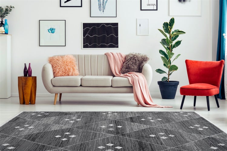 Wohnzimmer mit modernem grauen Teppich mit geometrischem Rautenmuster, einem beigen Sofa und einem roten Sessel in einer hellen Einrichtung.
