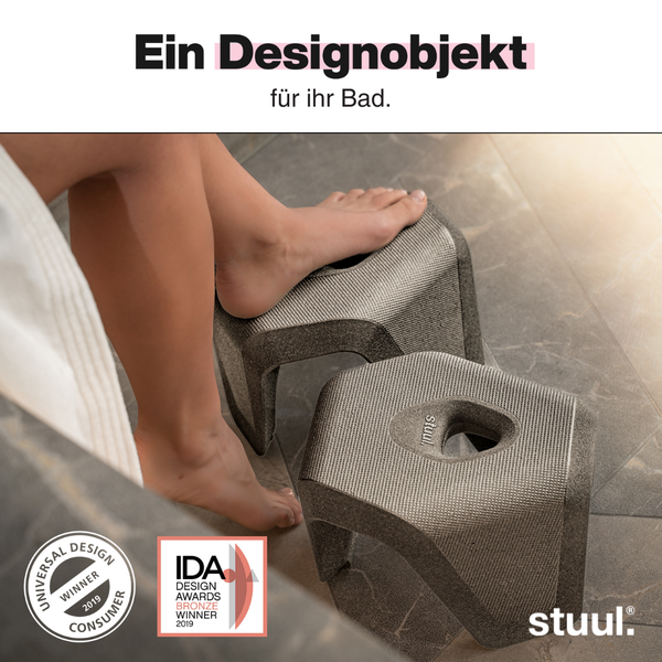 Zweiteiliger Toilettenhocker stuul im Badezimmer mit Füßen. Universal Design Winner 2019, IDA Design Awards Bronze Winner 2019, stuul Logo.