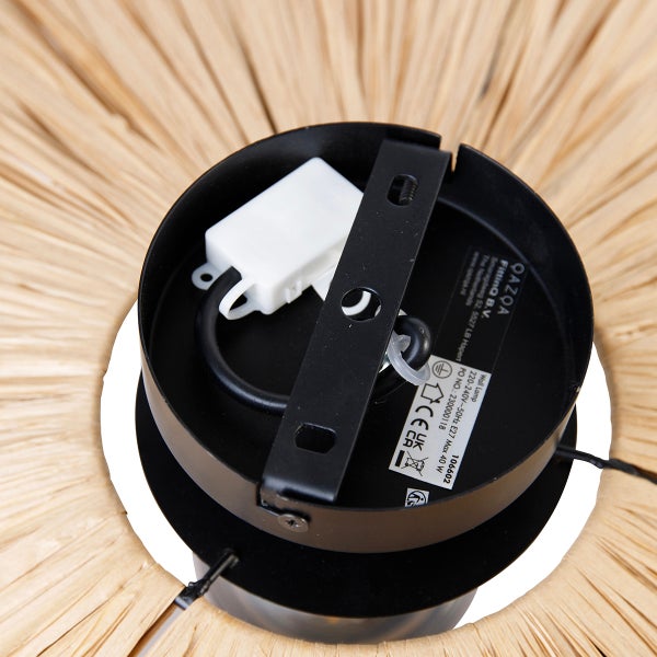 Detailansicht der runden schwarzen Wandhalterung einer Leuchte mit Montagebügel und Elektroanschluss vor einem Schirm aus Naturgeflecht.