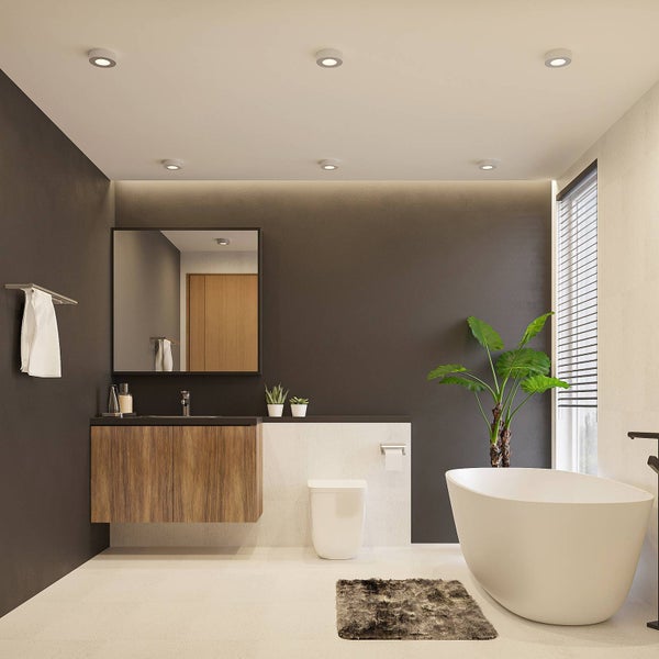 Modernes, helles Badezimmer mit freistehender Badewanne, Holz-Waschtisch, Spiegel, WC und Einbaustrahlern an der Decke.