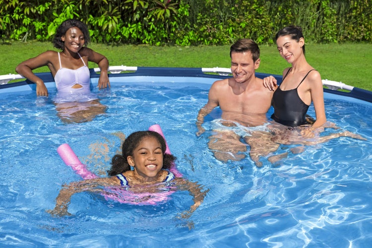 Personen in einem runden Aufstellpool in einem sonnigen Garten, ein Kind nutzt eine Poolnudel im Vordergrund.