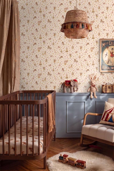 Kinderzimmer mit Zirkus Tapete, Gitterbett aus Holz, Schaukelstuhl und Dekorationselementen im Zirkusthema.