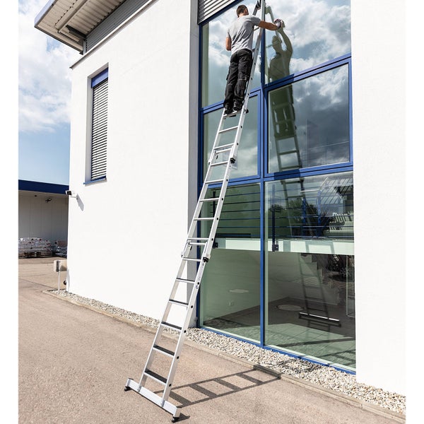 Mann reinigt Fenster an einem Gebäude mit einer Mehrzweckleiter.