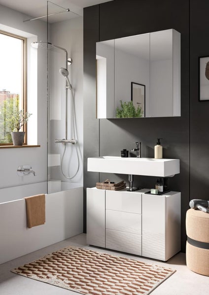 Modernes Badezimmer mit weißem Waschtischunterschrank, breitem Waschbecken, Spiegelschrank, Badewanne mit Glasduschwand und gemustertem Teppich.
