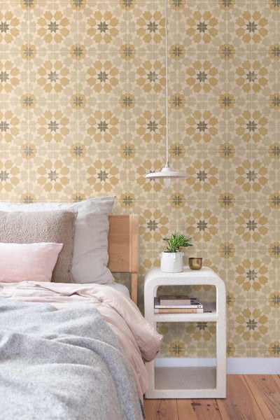 Helles Schlafzimmer mit Tapete mit orientalischem Muster, Bett mit hölzernem Kopfteil und weißem Beistelltisch.