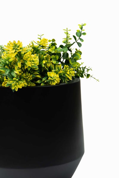 Künstliche Pflanze mit gelben Blüten in einem schwarzen Topf.