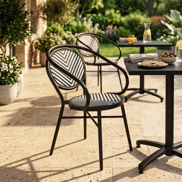 Moderner Bistrostuhl mit schwarz-weißem Fischgrätmuster auf einer hellen Terrasse mit Tisch und Gartenumgebung.