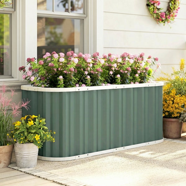 Grünes Hochbeet aus Metall mit rosa Blumen vor einer Hauswand auf einer Terrasse.