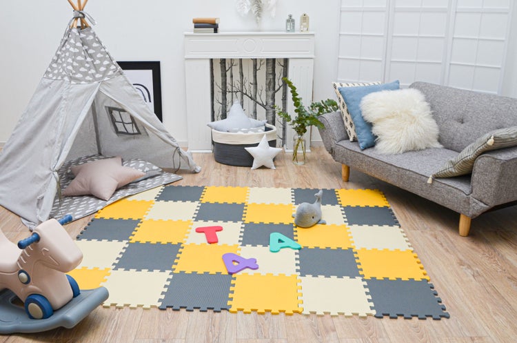 Helles Kinderzimmer mit einer Puzzle-Spielmatte aus weichem Schaumstoff, einem Spielzelt, einem Schaukelpferd und einem Sofa.