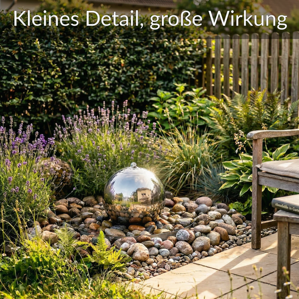 Edelstahl-Kugelfunktion auf Flusssteinen im hellen Garten mit Lavendel, Farnen und Holzmöbeln. Text: Kleines Detail, große Wirkung.