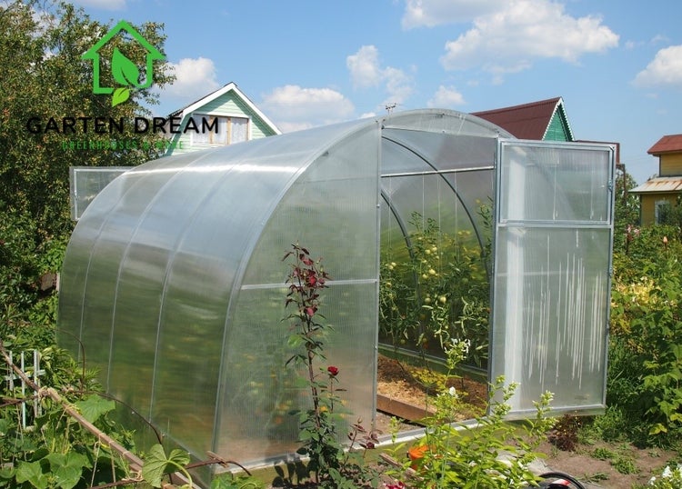 Gewächshaus mit geöffneter Tür in einem Garten.