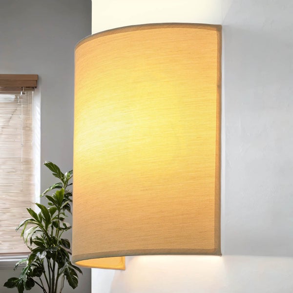 Beleuchtete Wandleuchte neben einer Zimmerpflanze