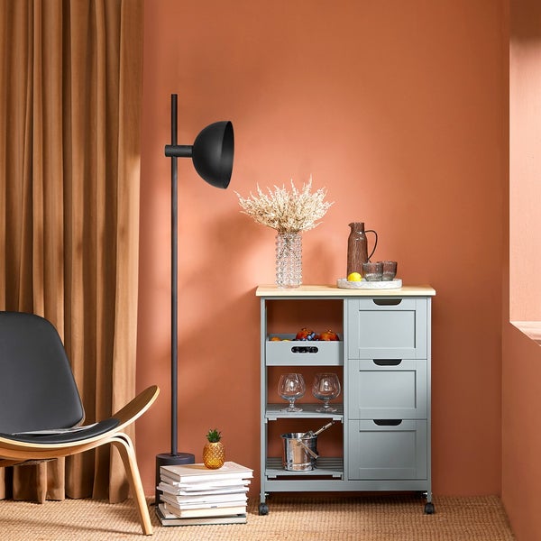 Innenaufnahme mit Servierwagen, Stehleuchte, Sessel und Dekoration in einem Zimmer