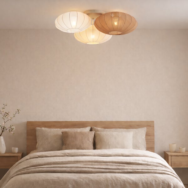 Moderne Deckenleuchte mit drei Stoffschirmen in Naturtönen, montiert in einem hellen, minimalistischen Schlafzimmer mit Holzbett.