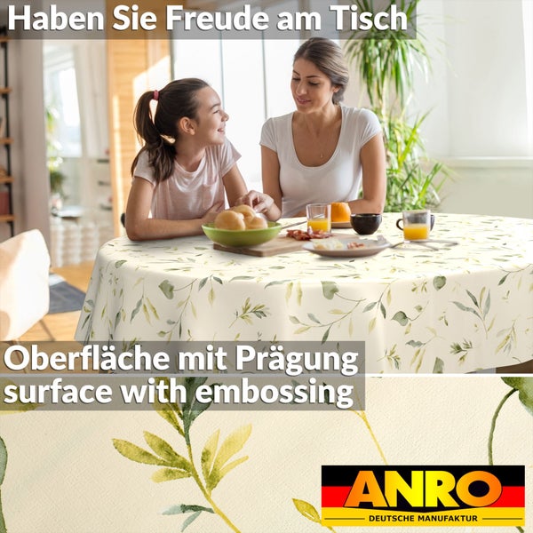 Runde Tischdecke mit Blättermuster auf einem Esstisch mit Frau und Kind in hellem Raum. Detail der Prägung. ANRO DEUTSCHE MANUFAKTUR Logo.
