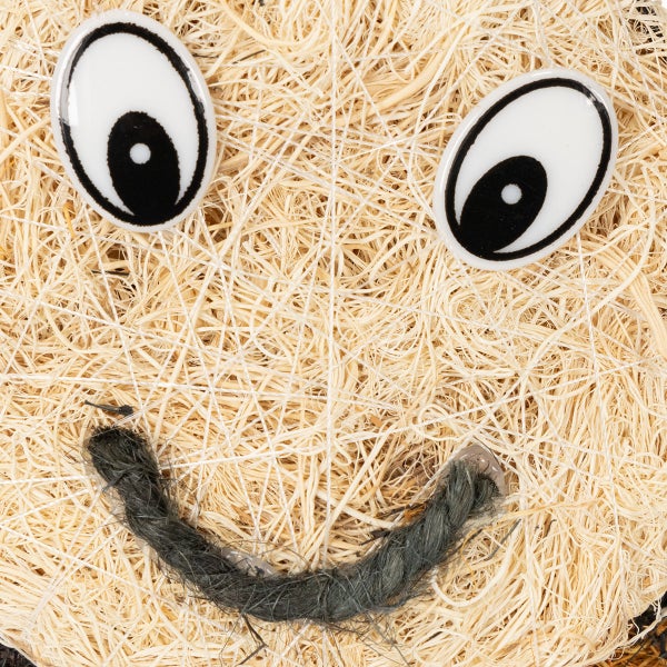 Dekoratives Kürbisgesicht aus Stroh mit Augen und Mund