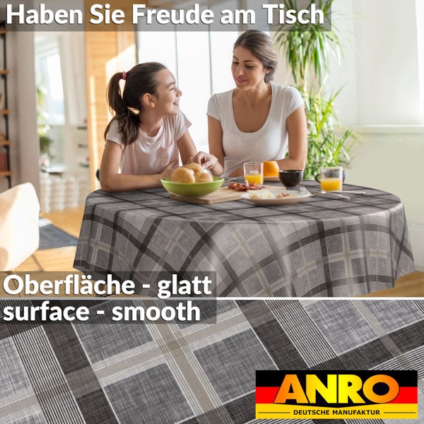 Runde Tischdecke mit grau-weißem Karomuster auf einem Esstisch in heller Wohnküche mit Frau und Kind. ANRO Deutsche Manufaktur Logo.
