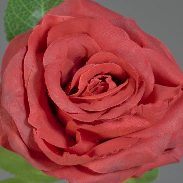 Künstliche rote Rose aus Textilmaterial mit grünen Blättern für die Dekoration.