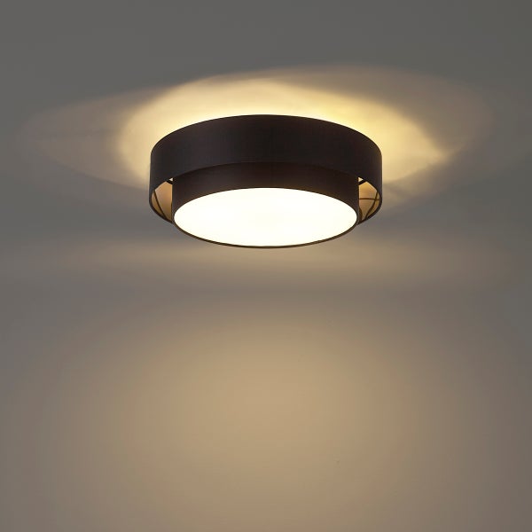 Runde Deckenleuchte aus schwarzem Metall mit warmweißem Lichtschein an der Decke.