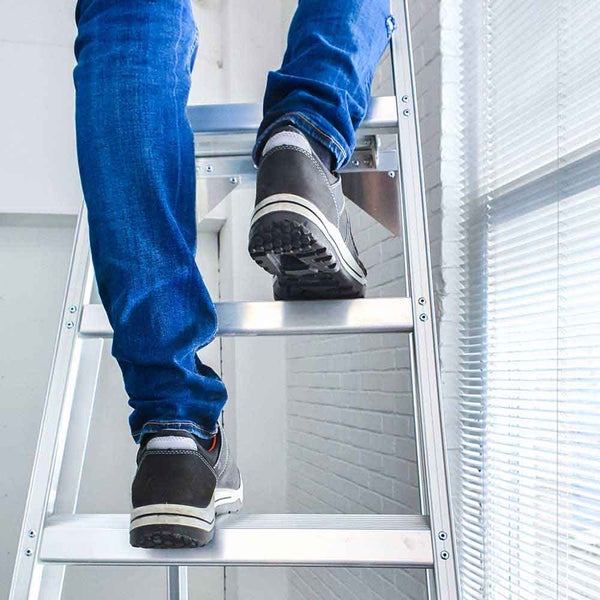 Eine Person steigt auf einer Aluminiumleiter.