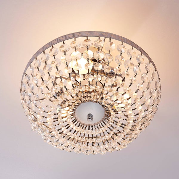 Deckenleuchte mit Metallrahmen im Mäander-Design und Kristallbehang, eingeschaltet an der Decke montiert.
