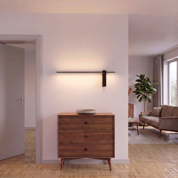 Moderne LED Wandleuchte mit indirektem Licht über einer hölzernen Kommode in einem hellen und stilvoll eingerichteten Wohnbereich.