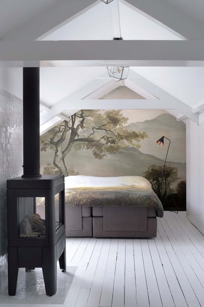 Schlafzimmer mit Kaminofen und Wandtapete mit Landschaftsmotiv