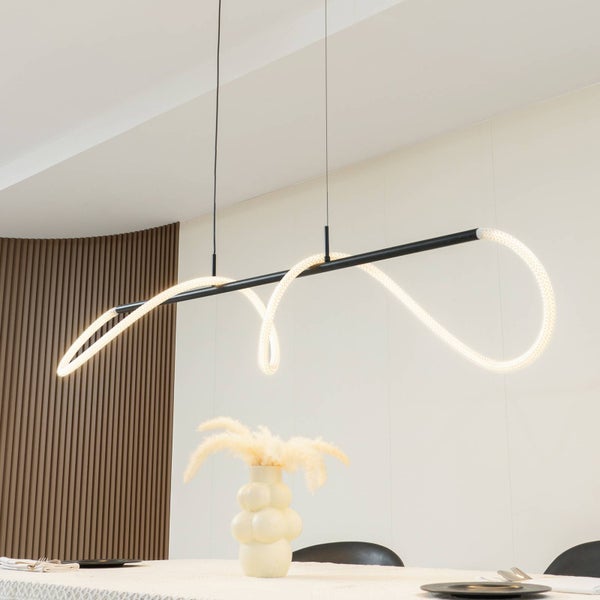Moderne LED-Pendelleuchte mit schwarzem Stab und flexibler, leuchtender Röhre in einem hellen Raum mit Holzlamellenwand und Esstisch.