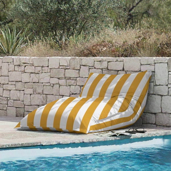 Gelb-weiß gestreifter Outdoor-Sitzsack am Pool vor einer Steinmauer.