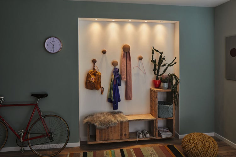 Organisierte Flurnische mit runden Wandhaken aus Holz, einer Sitzbank aus Holz und integrierter Beleuchtung.