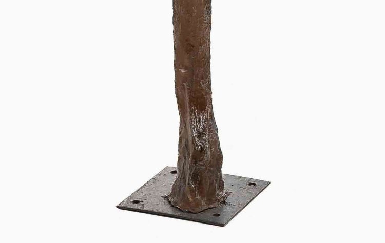 Detailansicht eines braunen Pfostens in Baumstammoptik mit quadratischer Metallbodenplatte und vier Montagelöchern.