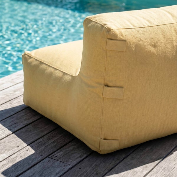 Gelber Outdoor-Lounge-Sessel aus strukturiertem Stoff auf einer Holzterrasse an einem Pool.