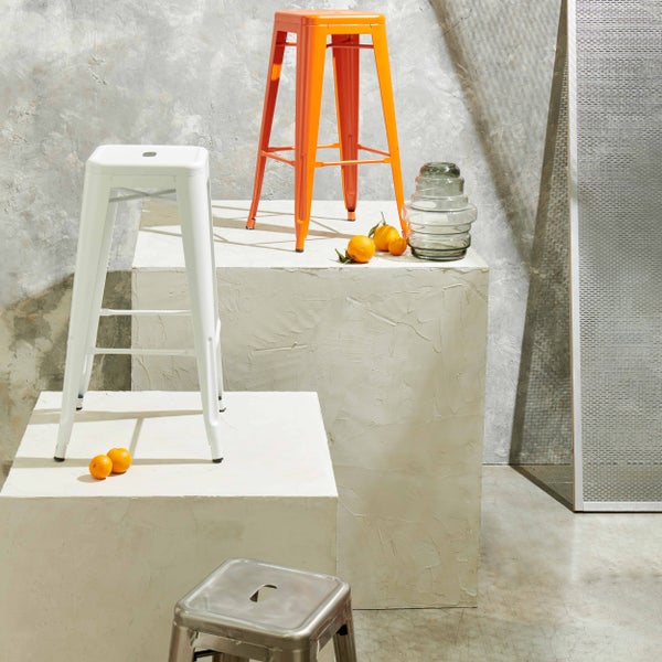 Drei Barhocker aus Metall im Industrial Design auf Betonpodesten mit einer Glasvase in einem hellen modern gestalteten Raum.