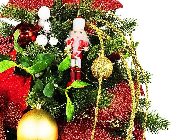 Festliches Weihnachtsgesteck mit Nussknacker Figur, Weihnachtskugeln, Tannenzweigen und glitzernden Dekorationselementen.