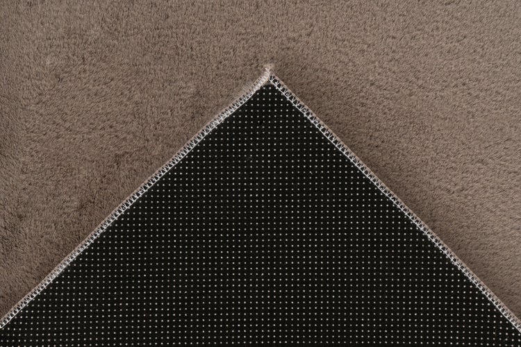Detailansicht eines Teppichs mit hochflorigem Flor und rutschfester Unterseite mit Noppen.