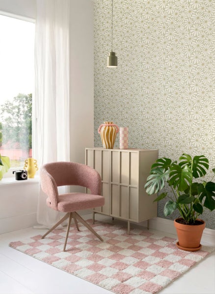 Helle Vliestapete mit Blumenmuster in einem modern eingerichteten Raum mit rosa Sessel, Sideboard und einer Monstera-Pflanze auf einem Teppich.