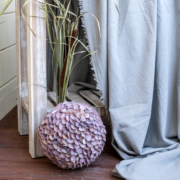 Dekorative Szene mit Kugel aus Muscheln, Schilf in Holzkiste und Stoff