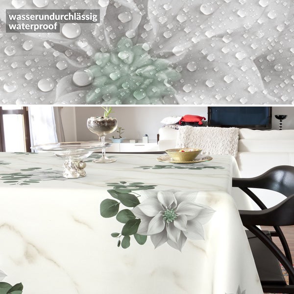 Wasserundurchlässige Tischdecke mit Marmor-Optik und Blumenmuster in einem Wohnzimmer, Detailaufnahme von Wassertropfen auf dem Material.