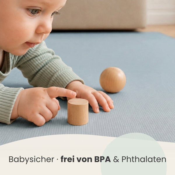 Kleinkind spielt auf einer Krabbelmatte mit Holzbausteinen, Produkt ist babysicher und frei von Bisphenol A sowie Phthalaten.