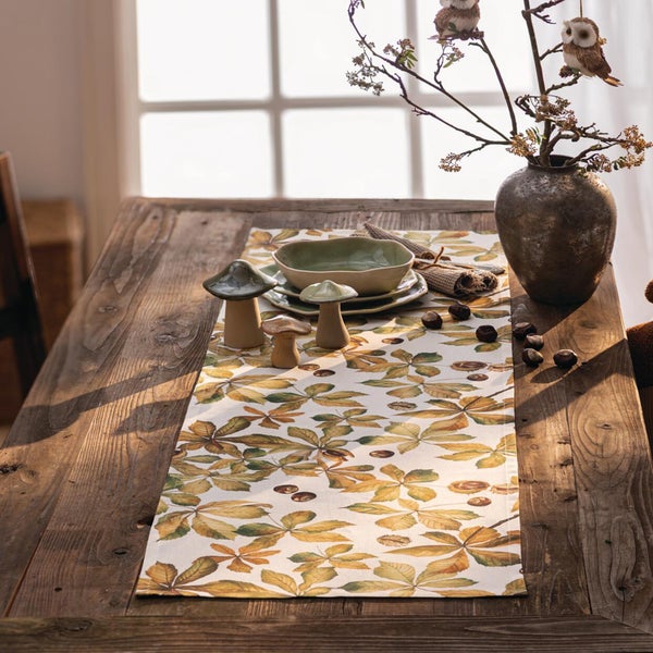Herbstlicher Tischläufer mit Kastanienblattmuster auf rustikalem Holztisch mit herbstlicher Dekoration.